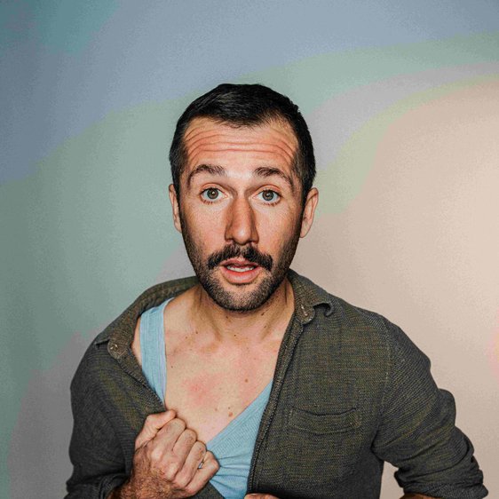 Portraitfoto von Stefan Leonhardsberger. Er schaut mit geöffnetem Mund in die Kamera, er trägt ein grünes Hemd, darunter ist ein blaues Unterhemd zu sehen.