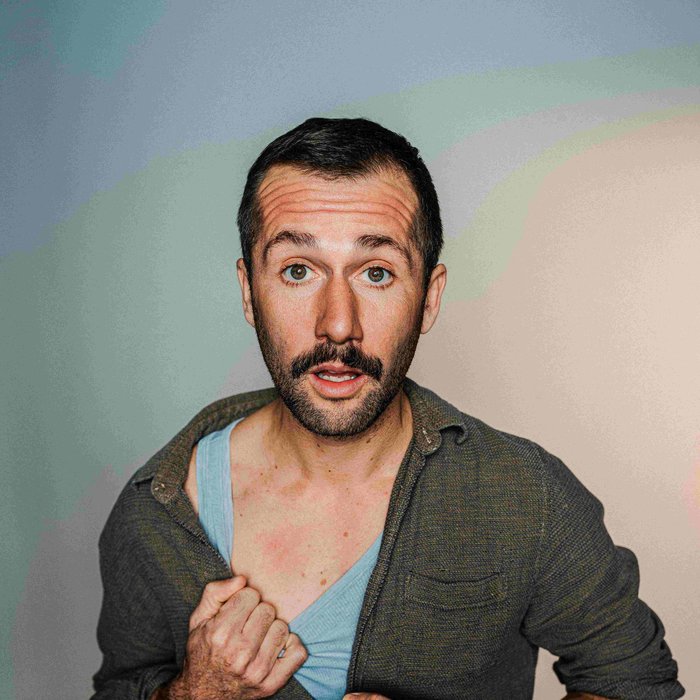 Portraitfoto von Stefan Leonhardsberger. Er schaut mit geöffnetem Mund in die Kamera, er trägt ein grünes Hemd, darunter ist ein blaues Unterhemd zu sehen.