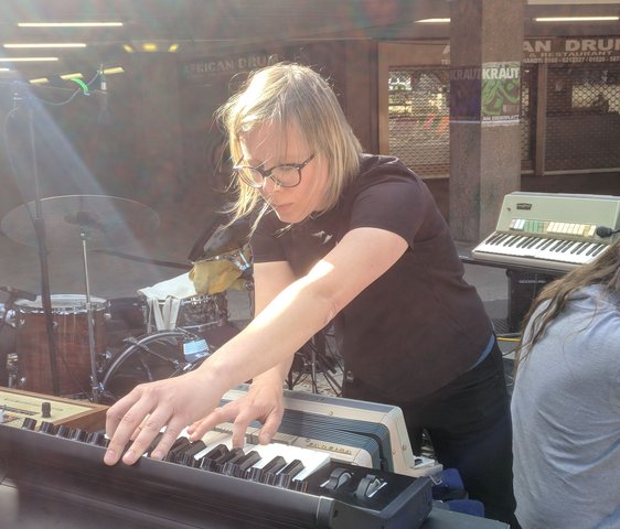 Komponistin arbeitet live an einem Mischpult und Keyboard in einem Studio- oder Proberaum.