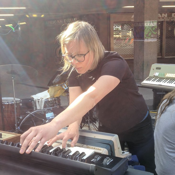 Komponistin arbeitet live an einem Mischpult und Keyboard in einem Studio- oder Proberaum.