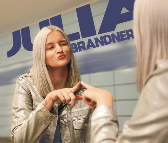 Julia Brandner vor einer Spiegelwand, sie berührt mit der Hand den Spiegel.