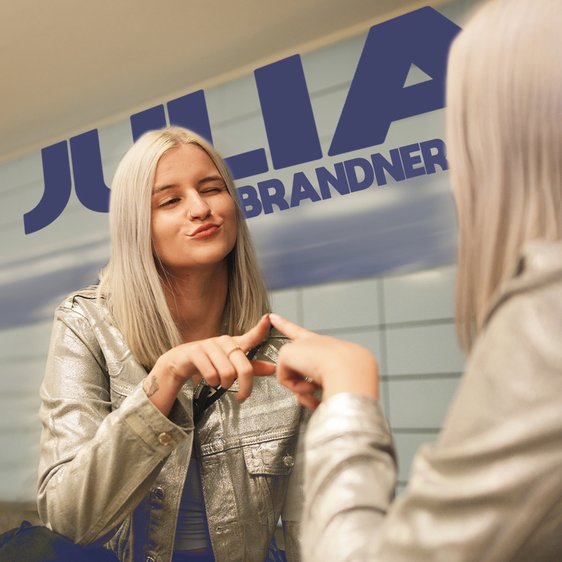 Julia Brandner vor einer Spiegelwand, sie berührt mit der Hand den Spiegel.