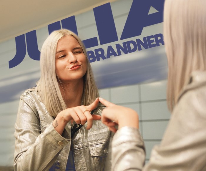 Julia Brandner vor einer Spiegelwand, sie berührt mit der Hand den Spiegel.