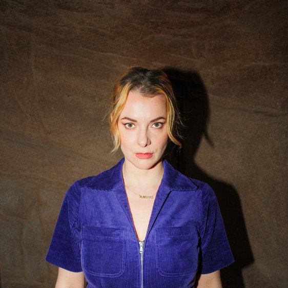 Portraitfoto von Kristina Bogansky, sie trägt einen blauen Kurzarm-Anzug und blickt in die Kamera.