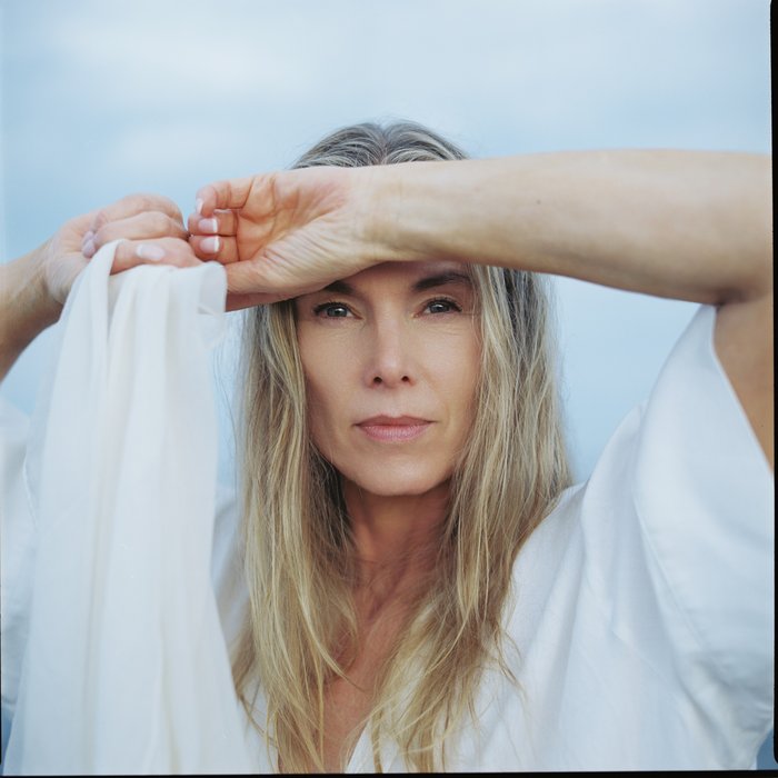 Rebekka Bakken mit langen blonden Haaren und weißer Kleidung hält sich die Hand an die Stirm