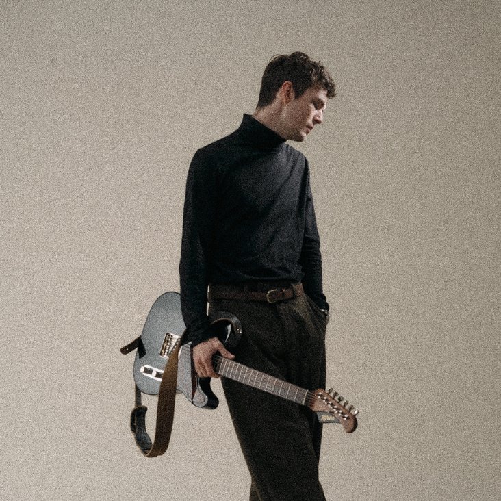 Ein Mann schlendet mit Gitarre im Arm