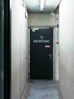 Schmaler Gang mit Tür „2 BACKSTAGE“ am Ende.