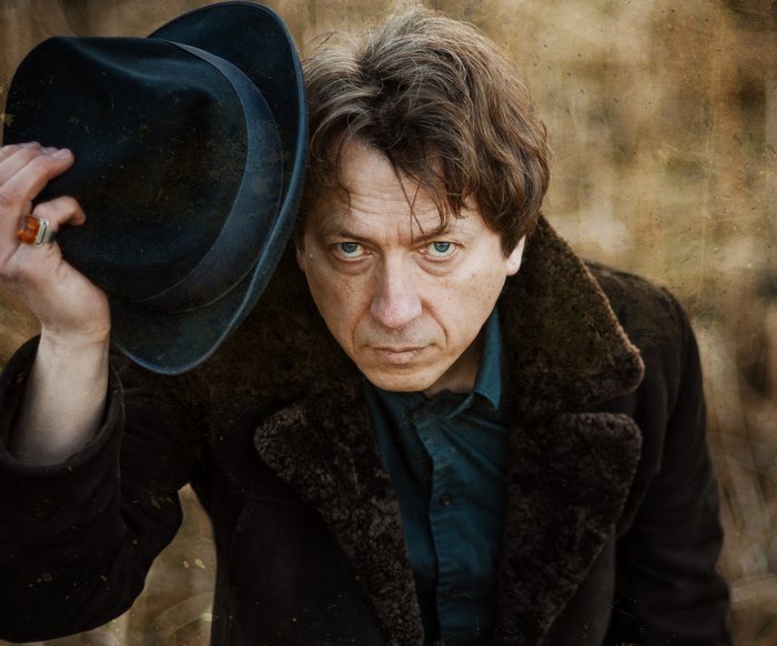 Ein Mann mit einem Pelzmantel zieht seinen Hut.