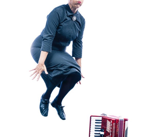Carmela de Feo springt in die Luft, neben ihr steht ein rotes Akkordeon auf dem Boden