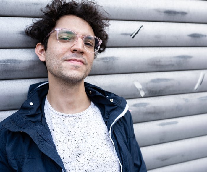 Porträt eines Mannes im Freien vor einer Metallwand, seitlicher Blick, natürliche Lichtstimmung.