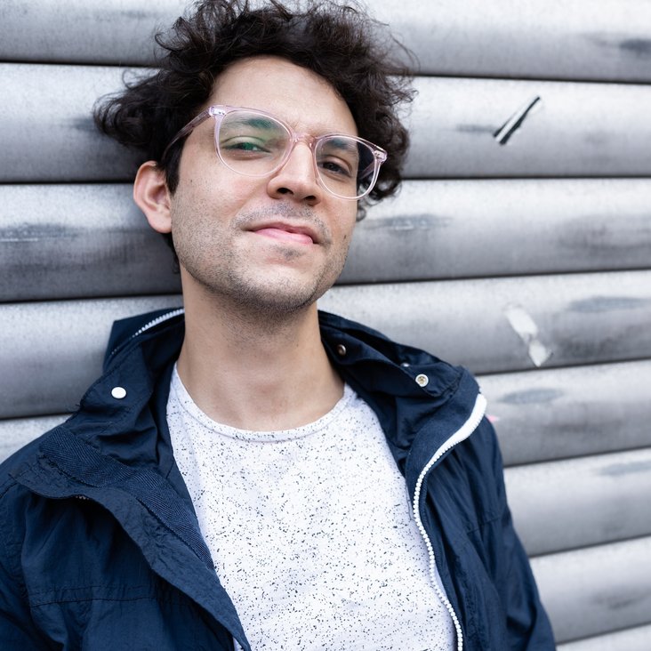 Porträt eines Mannes im Freien vor einer Metallwand, seitlicher Blick, natürliche Lichtstimmung.