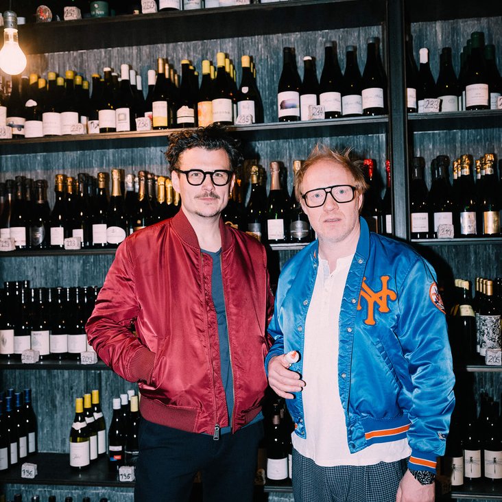 Manuel Rubey & Simon Schwarz vor einem großen Weinregal