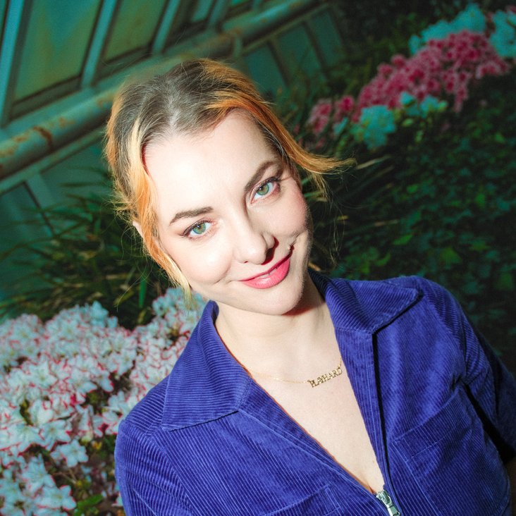 Portraitfoto von Kristina Bogansky, sie trägt einen blauen Kurzarm-Anzug und blickt in die Kamera.