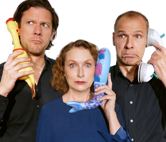 Die drei Protagonist:innen von Tauschrausch halten sich jeweils einen Telefonhörer, eine Gummihenne und einen aufblasbaren kleinen Wal als Telefon ans Ohr.