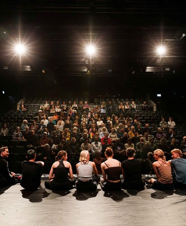 Eric Gauthier und die Gauthier Dance JUNIORS sitzen auf der Bühne, sie sind den Menschen im Publikum zugewandt und im Gespräch mit ihnen