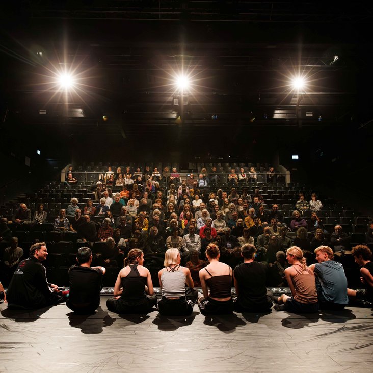 Eric Gauthier und die Gauthier Dance JUNIORS sitzen auf der Bühne, sie sind den Menschen im Publikum zugewandt und im Gespräch mit ihnen