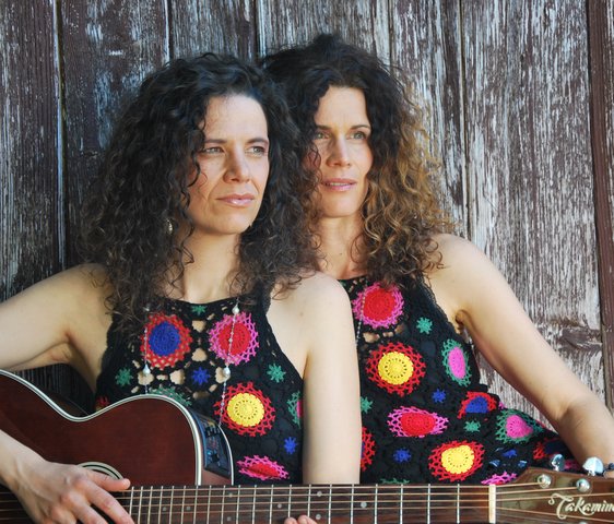 Die beiden Künstlerinnen von Vivid Curls, sie tragen beide dasselbe ärmellose Oberteil mit großen Punkten, eine von beiden hat eine Gitarre in der Hand