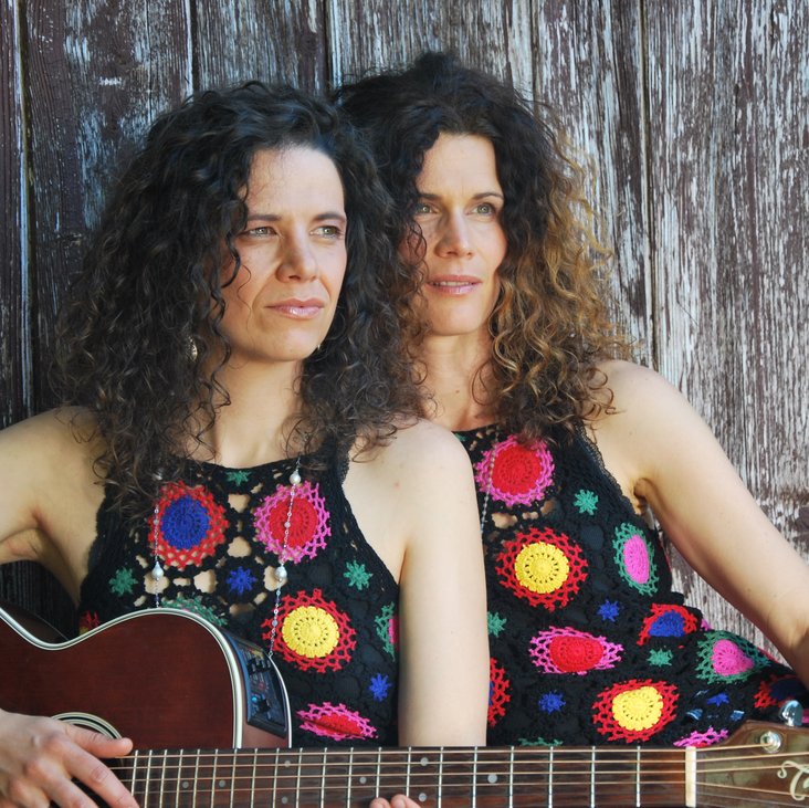 Die beiden Künstlerinnen von Vivid Curls, sie tragen beide dasselbe ärmellose Oberteil mit großen Punkten, eine von beiden hat eine Gitarre in der Hand