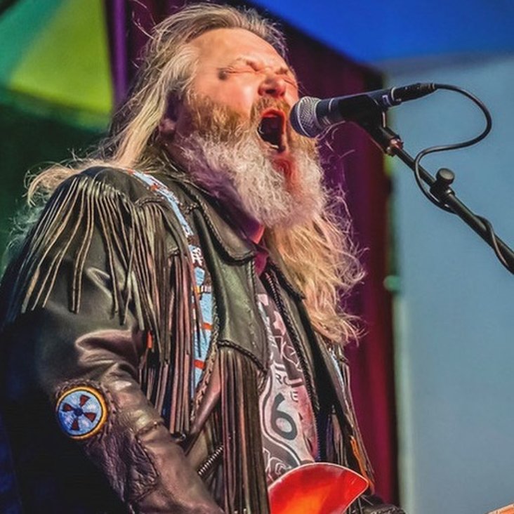 Ein graubärtiger Rocksänger singt leidenschaftlich in ein Mikrofon