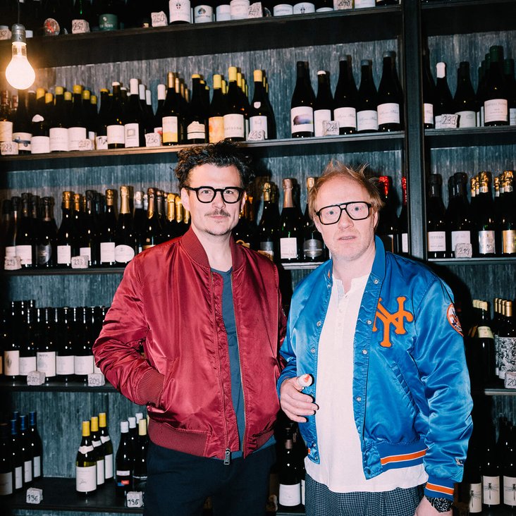 Manuel Rubey & Simon Schwarz vor einem großen Weinregal