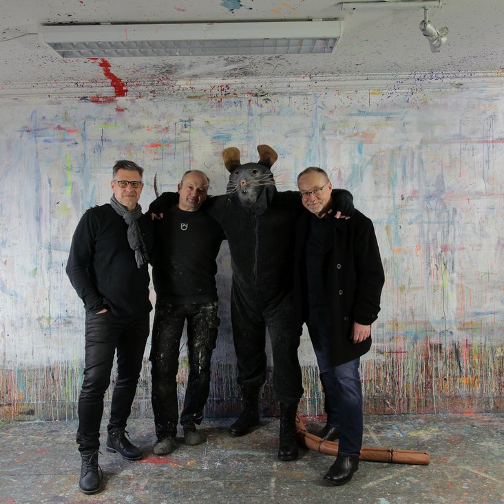 Gruppenfoto der vier Künstler vor einer Betonwand, einer trägt ein Rattenkostüm
