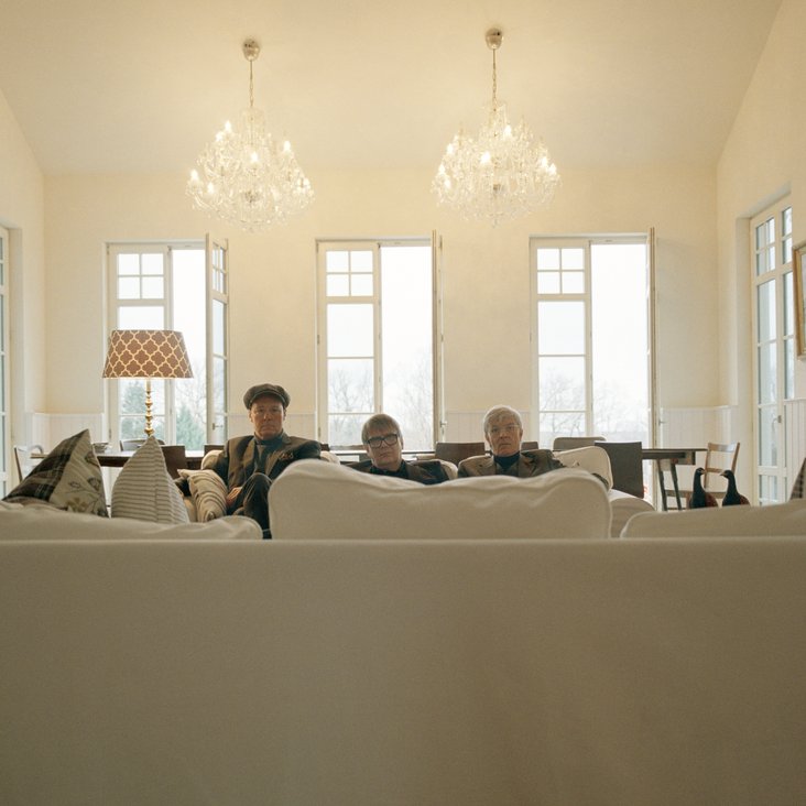 Drei Männer in einem edlen weißen Saal