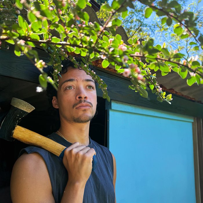 Aurel Mertz in ärmellosem T-Shirt und ein Beil in der Hand, das er über die Schulter gelegt hat.