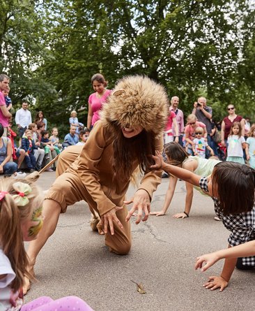 Tänzerin als Löwe verkleidet tanzt mit Kindern