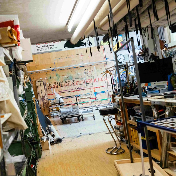 Werkstatt mit Materialregalen, Arbeitstischen und Werkzeugen.