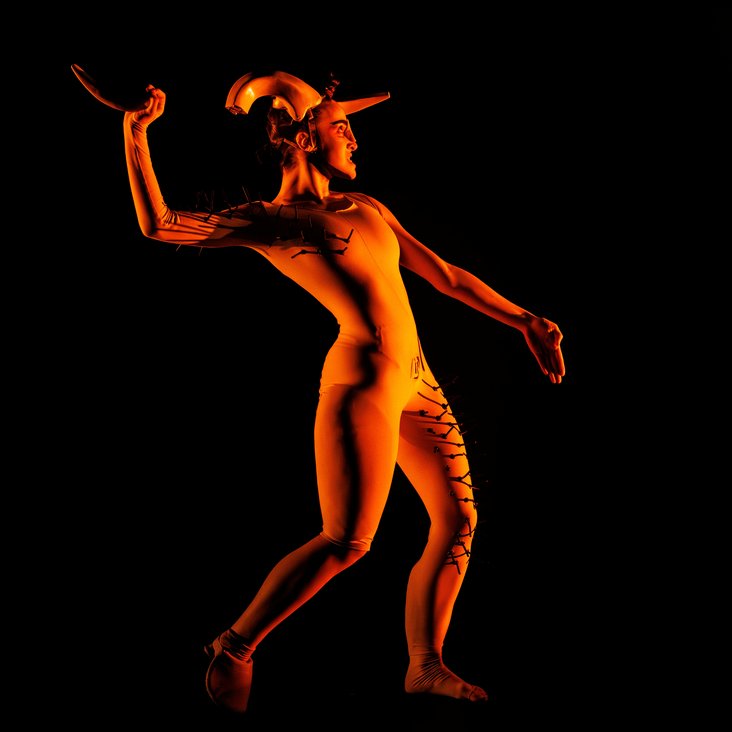 Tänzerin in Kostüm auf der Bühne, der Boden ist schwarz und die Bühne ist professionell ausgeleuchtet.