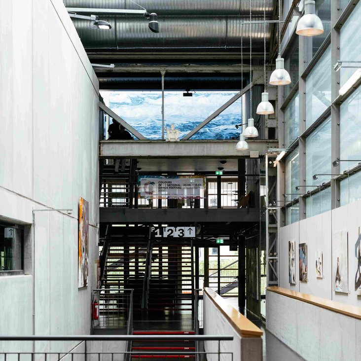 Heller Innenbereich mit Treppe, Galerie und Glasfassade.