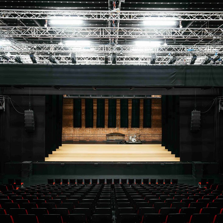 Blick aus Zuschauerraum auf beleuchtete Bühne im Theaterhaus.