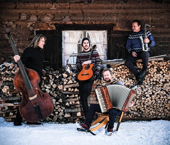 Die Musiker von Quadro Nuevo mit ihren Instrumenten im Schnee vor einer Hütte