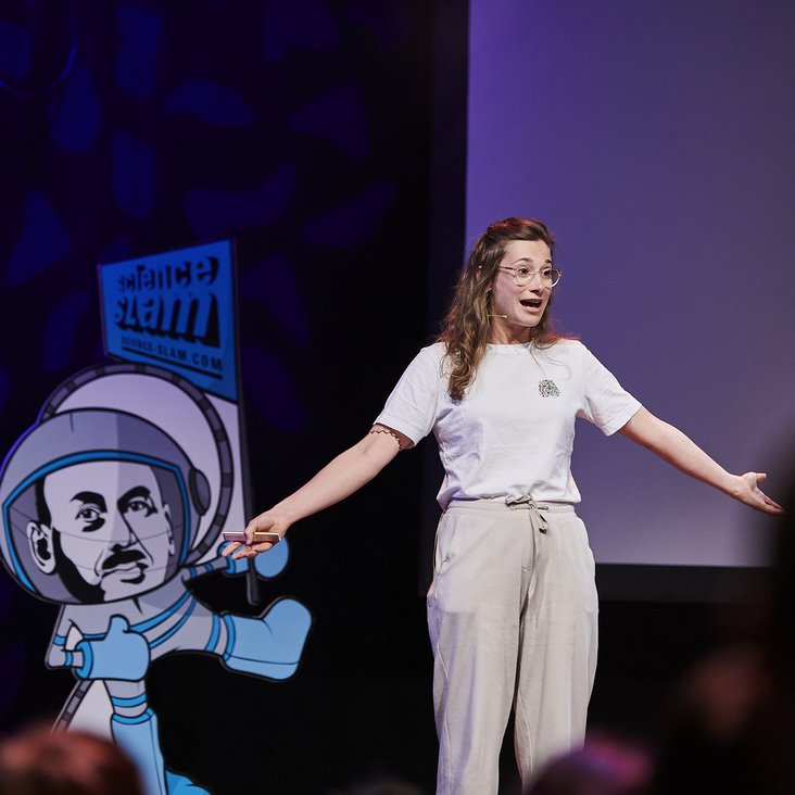 Teilnehmende des Science Slam auf der Bühne vor Publikum