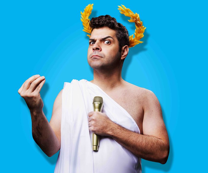 Ein Mann in einem alten griechischen Gewand hält ein Mikrophon