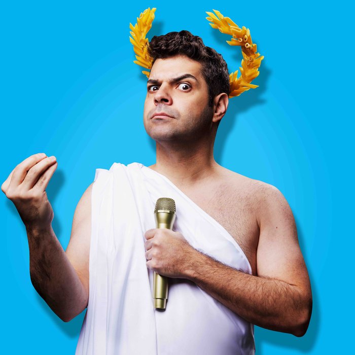Ein Mann in einem alten griechischen Gewand hält ein Mikrophon