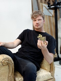 DJ, Produzent und Rapper Dexter auf einem goldenen Sessel mit einem Glas in der Hand