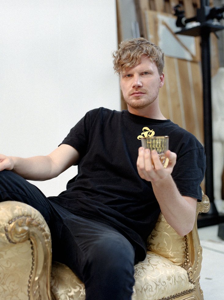 DJ, Produzent und Rapper Dexter auf einem goldenen Sessel mit einem Glas in der Hand