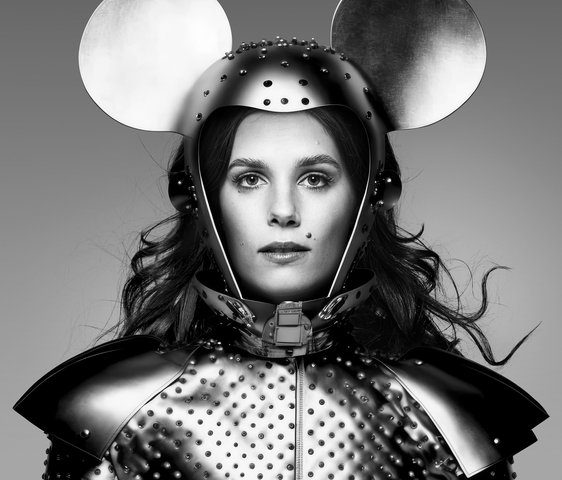 Ein schwarz-weiß Foto von Autorin und Kulturwissenschaftlerin Tara-Louise Wittwer in einem Kostüm das eine Mischung aus Ritterrüstung und Mäuse-Ohren zeigt