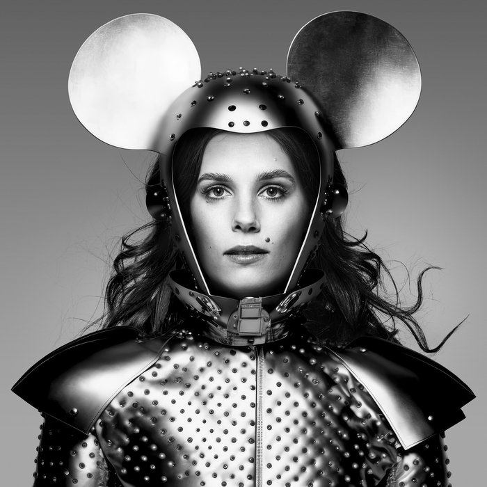 Ein schwarz-weiß Foto von Autorin und Kulturwissenschaftlerin Tara-Louise Wittwer in einem Kostüm das eine Mischung aus Ritterrüstung und Mäuse-Ohren zeigt