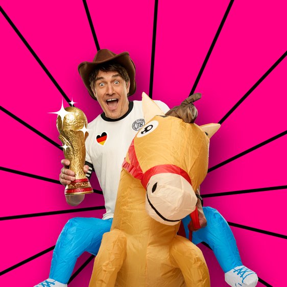 Matze Knop mit Cowboy-Hut, Deutschland-Trikot und Pokal auf einem aufblasbaren Pferd