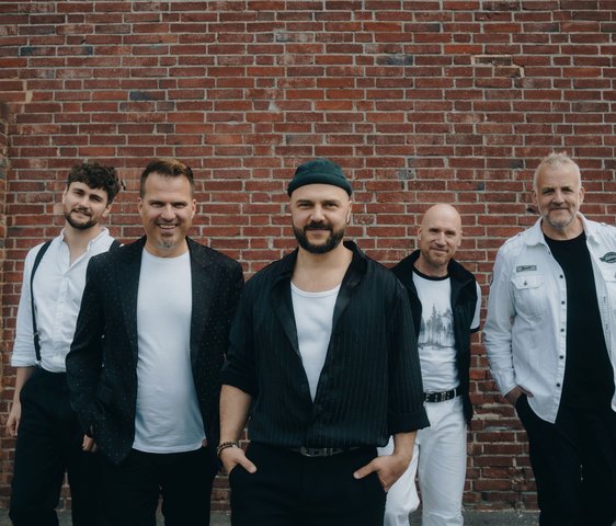 Die Mitglieder der Band "alte bekannte" stehen vor einer roten Backsteinwand