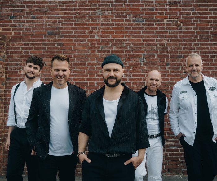 Die Mitglieder der Band "alte bekannte" stehen vor einer roten Backsteinwand