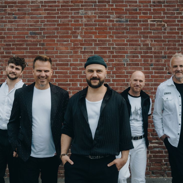 Die Mitglieder der Band "alte bekannte" stehen vor einer roten Backsteinwand