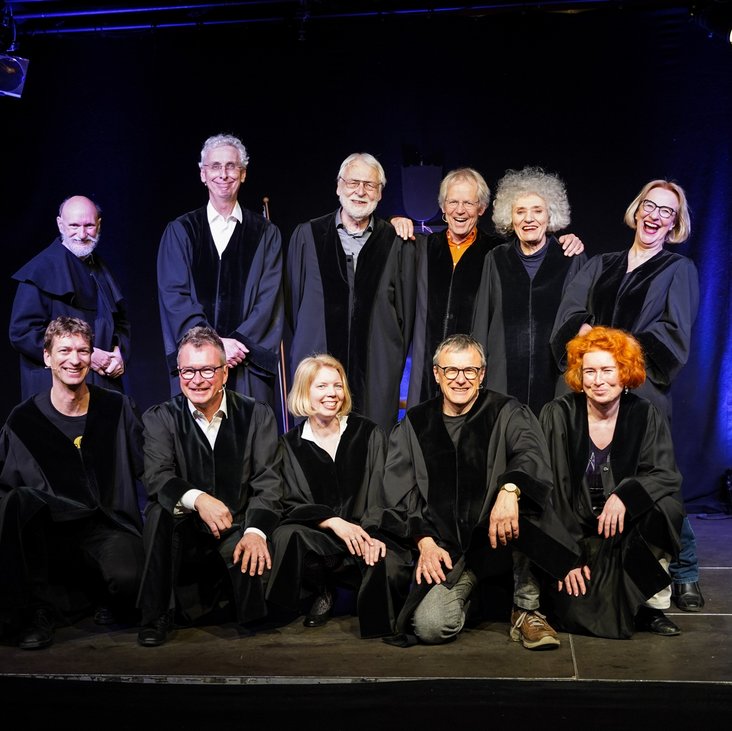 Eine Gruppe von Richter:innen in Roben stehen für ein Gruppenbild auf einer Theaterbühne