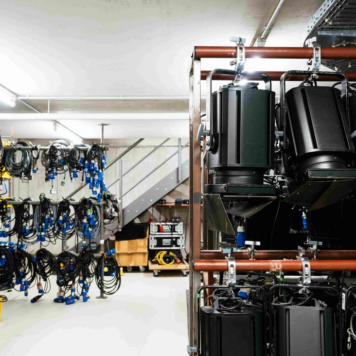 Regale mit Scheinwerfern und Kabeln in technischem Lager.