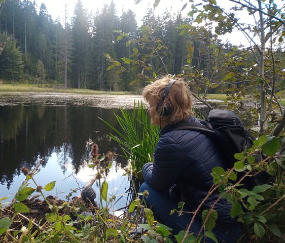 Kirsten Reese am Ufer eines Sees oder Teichs im Wald