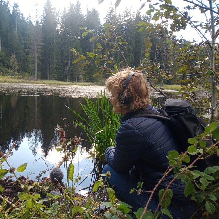 Kirsten Reese am Ufer eines Sees oder Teichs im Wald