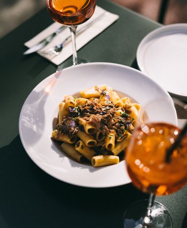 Teller mit Pasta und Glas auf gedecktem Tisch.