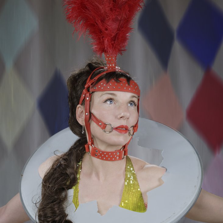 Meret Becker mit einem zirkusartigen Kostüm blickt verträumt nach oben
